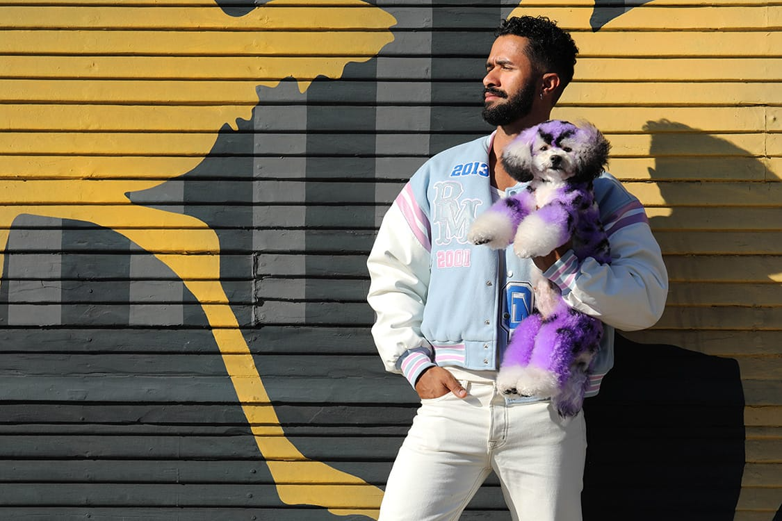Gabriel Feitosa holding a poodle with purple hair