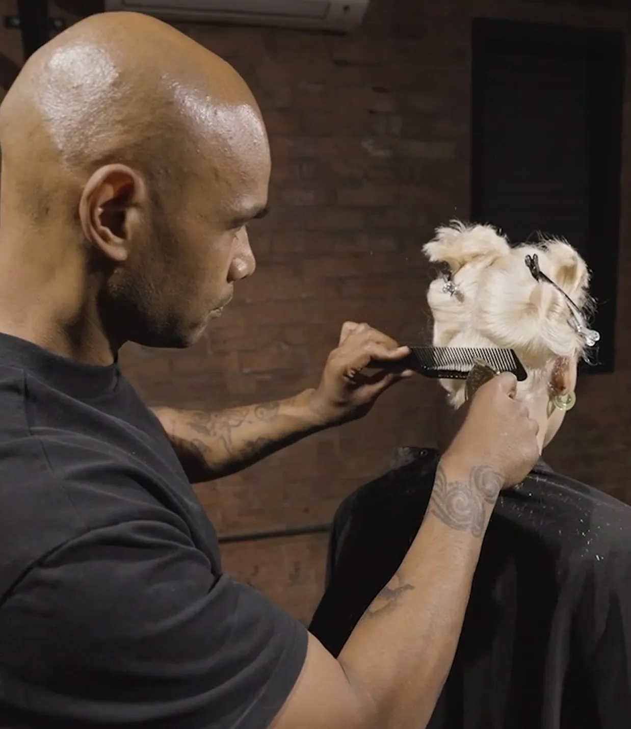 Andis International Artistic Lead, Kevin Luchman in process of cutting blonde woman's hair